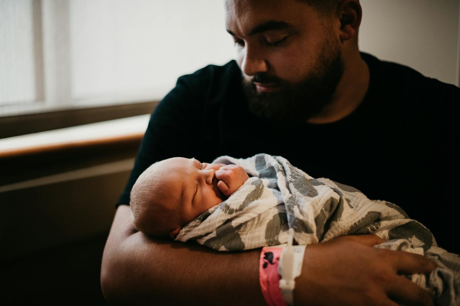 A father gazing at his swaddled newborn